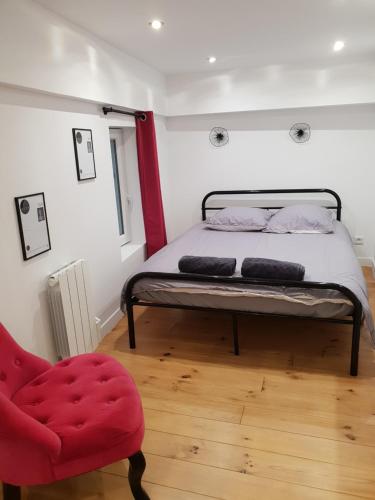 a bedroom with a bed and a red chair at Appart Jardin en Ville Cœur de Nantes in Nantes