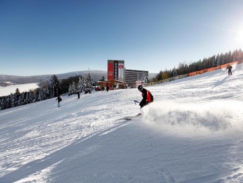 a group of people skiing down a snow covered slope at AHORN Hotel Am Fichtelberg in Kurort Oberwiesenthal