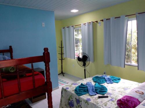 a bedroom with a bed and two windows at Nena's Suítes in Praia de Araçatiba