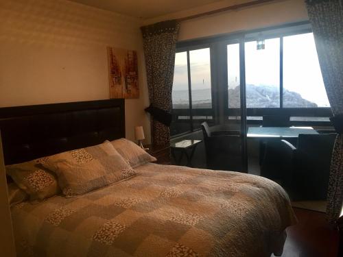 a bedroom with a bed with a desk and a window at Beachfront Apartment Reñaca Chile in Viña del Mar
