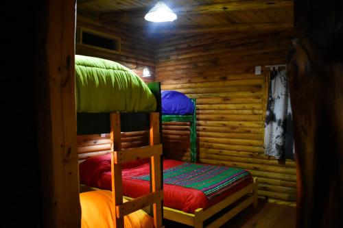 a room with two bunk beds in a log cabin at Infinito Chill0ut in San Marcos Sierras