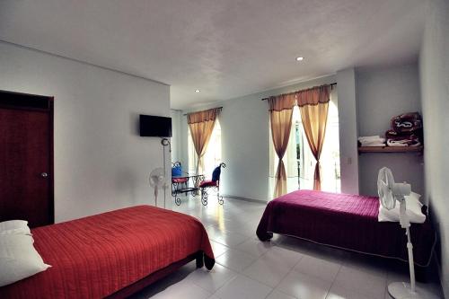 a bedroom with two beds with red sheets and a tv at Bungalows de KQ in Xilitla