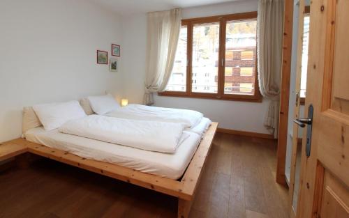 - une chambre avec un lit doté de draps blancs et une fenêtre dans l'établissement Chalavus, à Saint-Moritz