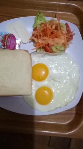 a plate with two eggs and a sandwich and salad at Pujihouse One in Legian