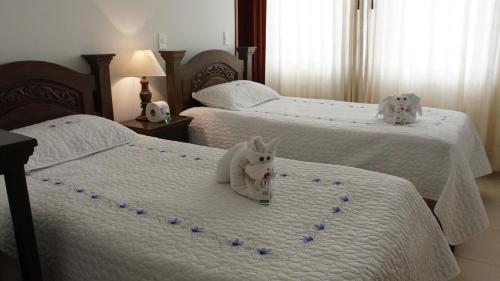 two beds with white cats sitting on top of them at Hotel Sipa in Duitama