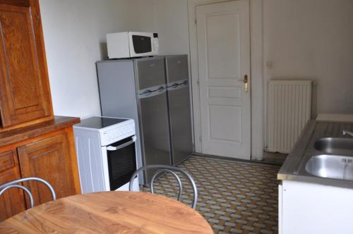 Il comprend une cuisine équipée d'un réfrigérateur et d'une table avec des chaises. dans l'établissement Château De La Croix Bizet, à Moulineaux