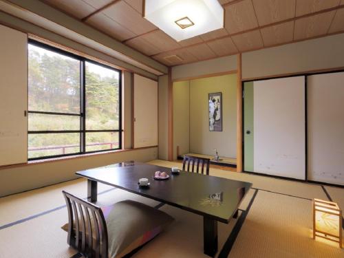 a room with a table and chairs and windows at Kagamigaike Hekizantei in Nihommatsu