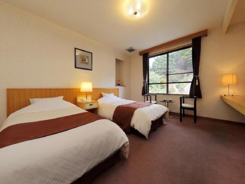 una camera d'albergo con due letti e una finestra di Kagamigaike Hekizantei a Nihommatsu