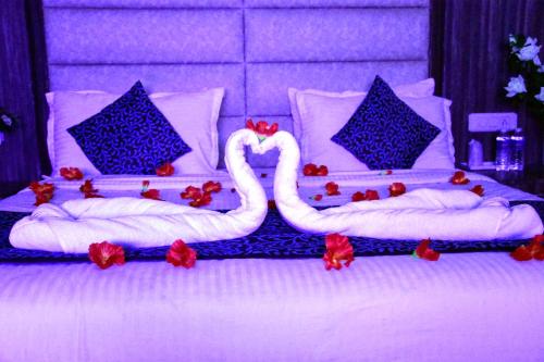two swans are sitting on a bed with red flowers at Rama Trident, Katra in Katra