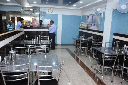 een restaurant met tafels en stoelen en mensen die aan een toonbank staan bij Green Grande Inn in Chennai