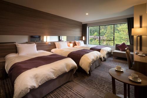 a hotel room with three beds and a window at Hotel Koyokan in Hanamaki