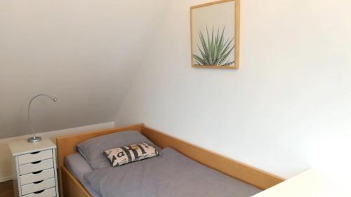 a bed in a room with a nightstand and a cactus picture at Elbe19 Ferienwohnung in Marschacht