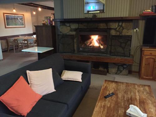 a living room with a couch and a fireplace at Winterhaus Lodge Thredbo Village in Thredbo