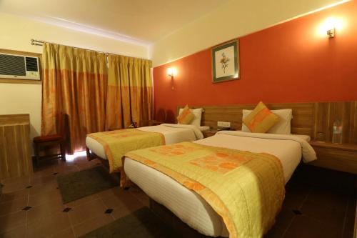 two beds in a hotel room with red walls at VITS Kamats Resort, Silvassa in Silvassa