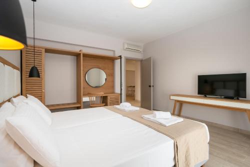 a bedroom with a white bed and a flat screen tv at Electra Apartments in Sidari