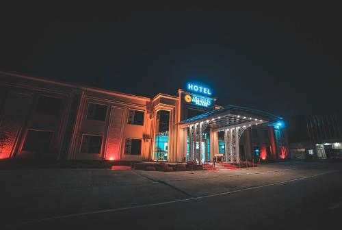 a hotel building with a neon sign at night at Asmald Palace Hotel in Kokand