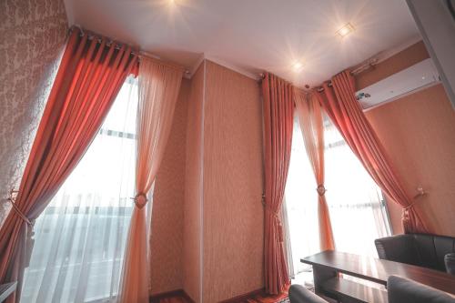 a room with two large windows with orange curtains at Asmald Palace Hotel in Kokand