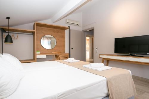 a bedroom with a large white bed and a flat screen tv at Electra Apartments in Sidari