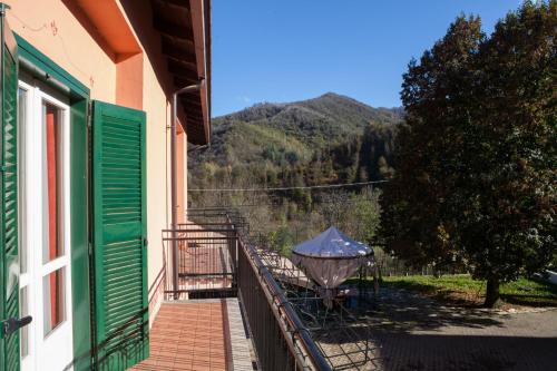 a balcony of a house with a table and an umbrella at B&B Casa dell'Orso in Lurisia