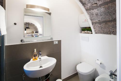 a bathroom with a sink and a toilet and a mirror at The House in Catania
