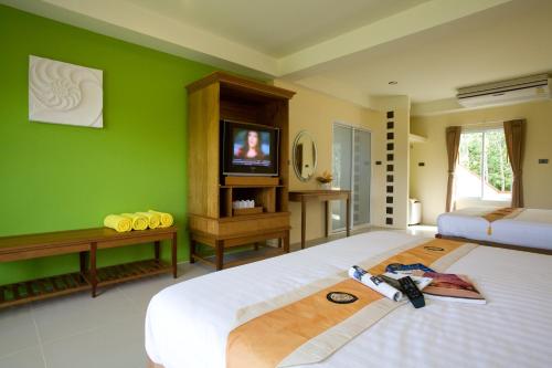 a bedroom with green walls and a bed with a television at Para Resort in Ko Chang