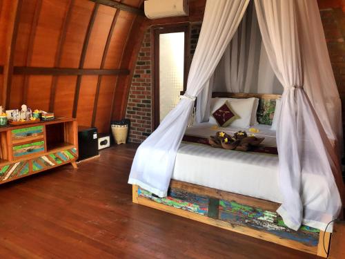 a bedroom with a bed with a mosquito net at Balangan Sea View Bungalow in Jimbaran