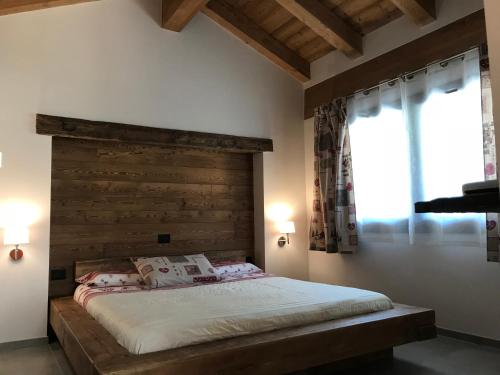 a bedroom with a bed with a wooden headboard and two windows at L'armonia della natura in Aosta