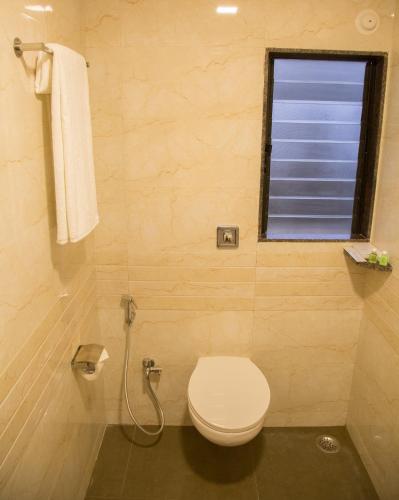 a bathroom with a toilet and a window at Hotel Nirvana in Alibaug