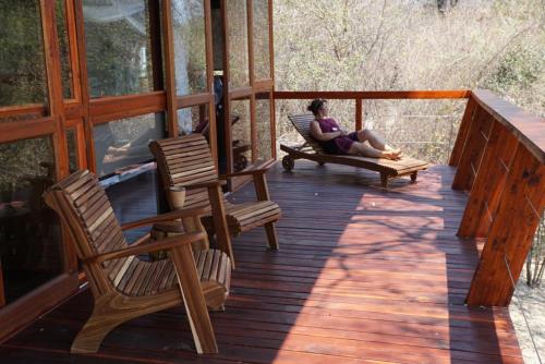 a woman sitting on the porch of a cabin at RiverDance Lodge in Mamono