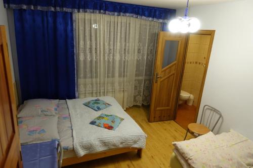 sypialnia z łóżkiem i oknem z niebieskimi zasłonami w obiekcie Pokoje u Szlachty w mieście Szczawnica