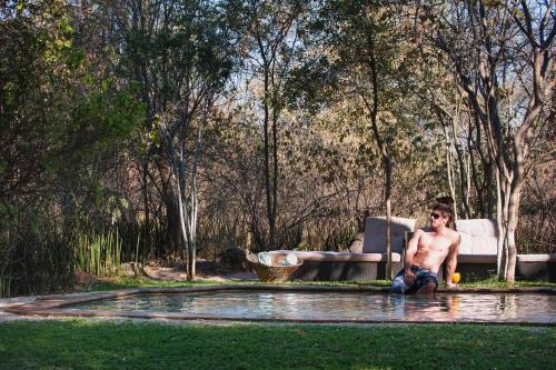 a shirtless man sitting in a pool of water at RiverDance Lodge in Mamono