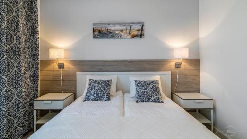 a bedroom with a white bed with two night stands at hvile 104 - Gdańsk TRE MARE in Gdańsk