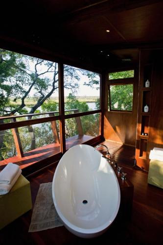 a bathroom with a large white tub in a room with windows at RiverDance Lodge in Mamono