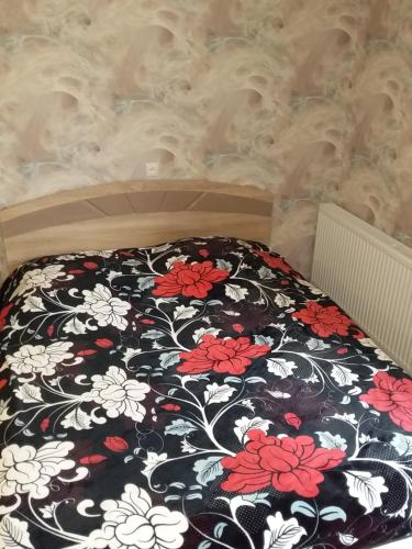 a bed with a black and white blanket with red and white flowers at Guest House Medea in Tʼelavi