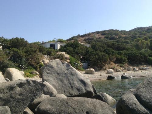 a group of rocks in the water with a house at Sa Maluni in Geremeas