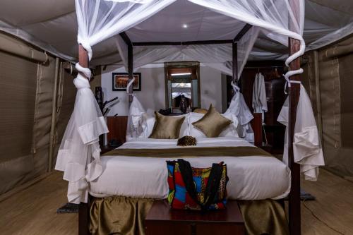 1 dormitorio con cama con dosel en una tienda de campaña en La Maison Royale Masai Mara, en Sekenani