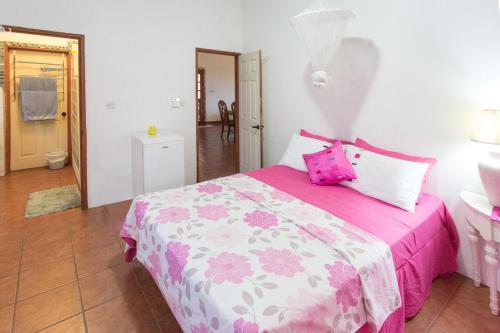 Un dormitorio con una cama rosa y blanca con almohadas rosas en Palm View, en Laborie