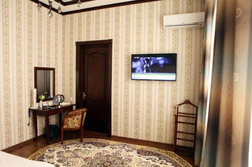 una camera con TV su una parete e sedia di Hotel Naxshab a Karshi