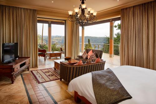 a bedroom with a bed and a tv and a balcony at AmmaZulu African Palace in Kloof
