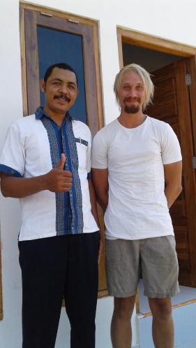 two men standing next to each other in front of a door at Tarsan Homestay in Labuan Bajo