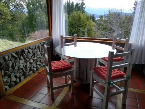 una mesa y 2 sillas en un porche con ventana en Albatros cabaña, en Villa La Angostura