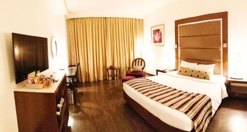 a hotel room with a large bed and a desk at Royal Orchid Central, Pune in Pune
