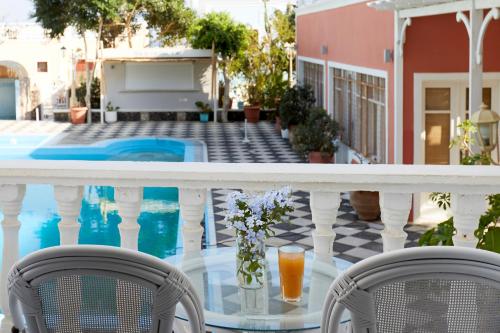 a balcony with two chairs and a glass table with flowers at Blue Sea Hotel in Kamari