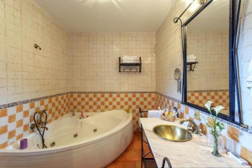 Un baño con una bañera grande y un lavabo. en Hotel Rural Los Angeles en Las Hurdes, en Vegas de Coria