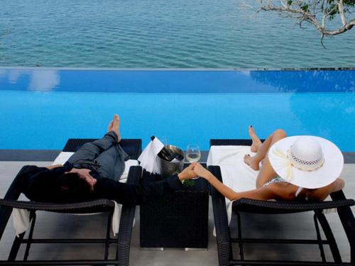 a man and woman laying on chairs at a table at Cape Sienna Phuket Gourmet Hotel & Villas - SHA Extra Plus in Kamala Beach