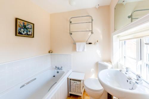 a bathroom with a tub and a sink and a toilet at 5 Coastguard Cottages in Aldeburgh