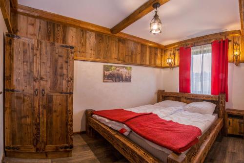 a bedroom with a bed with wooden walls and a red curtain at Jaworczański Raj pod Wysoką - z Sauną przy Wyciągu in Szczawnica