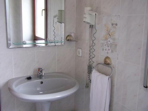 ein weißes Badezimmer mit Waschbecken und Spiegel in der Unterkunft Hotel Alemar in Somo