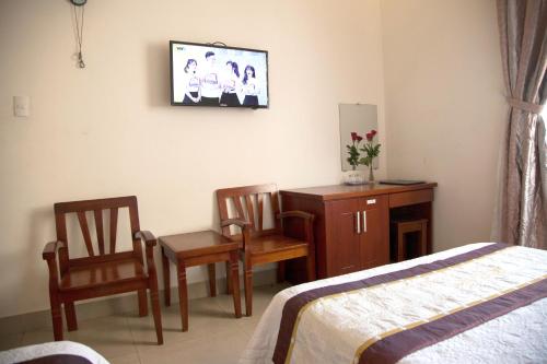 ダナンにあるHoang Thuy Sinh Hotelのベッドルーム1室(ベッド1台、椅子2脚、ドレッサー付)