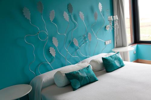 um quarto com uma cama com uma parede azul em Hotel Araz em Las Rozas de Valdearroyo